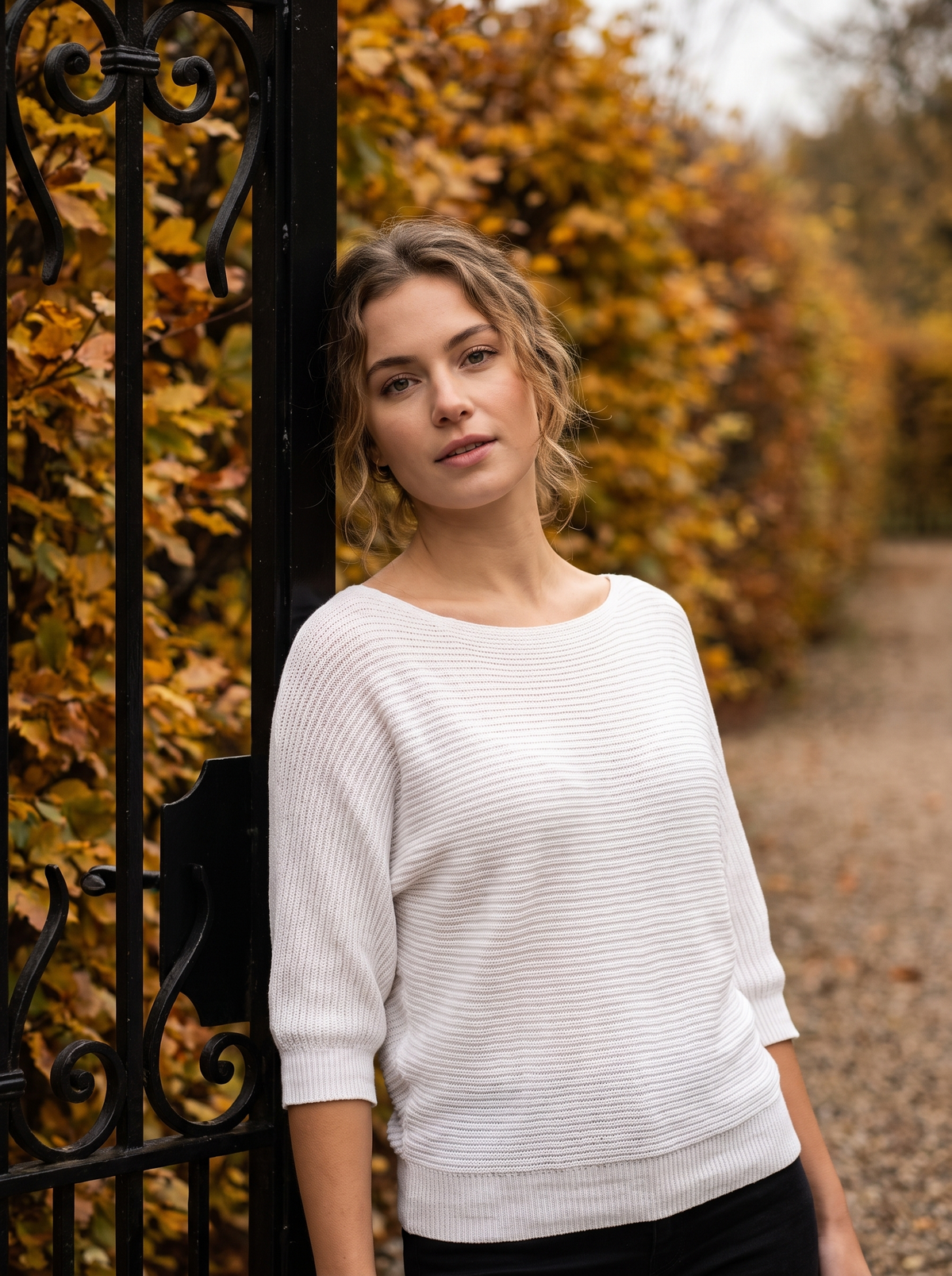 Giselle white three quarter sleeve knit sweater worn by a model at a park gate in autumn