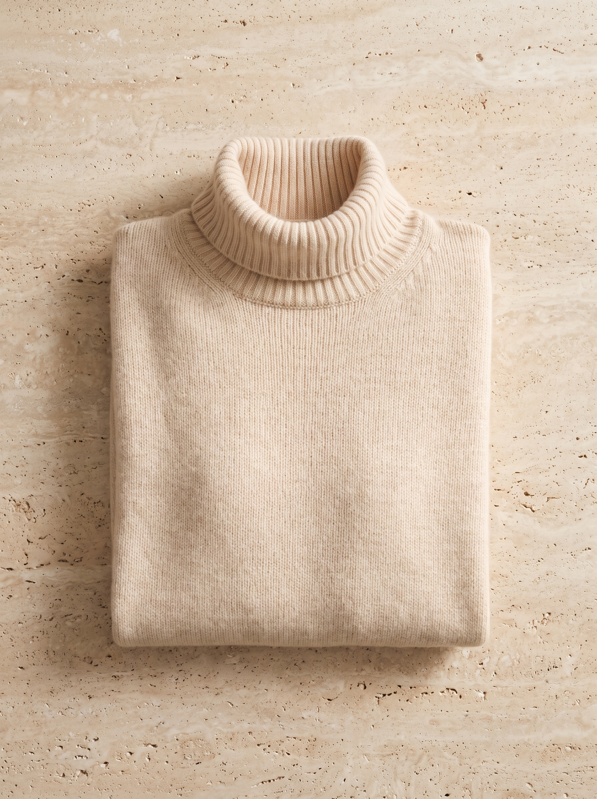 Cosima roll neck cashmere sweater folded neatly on a table