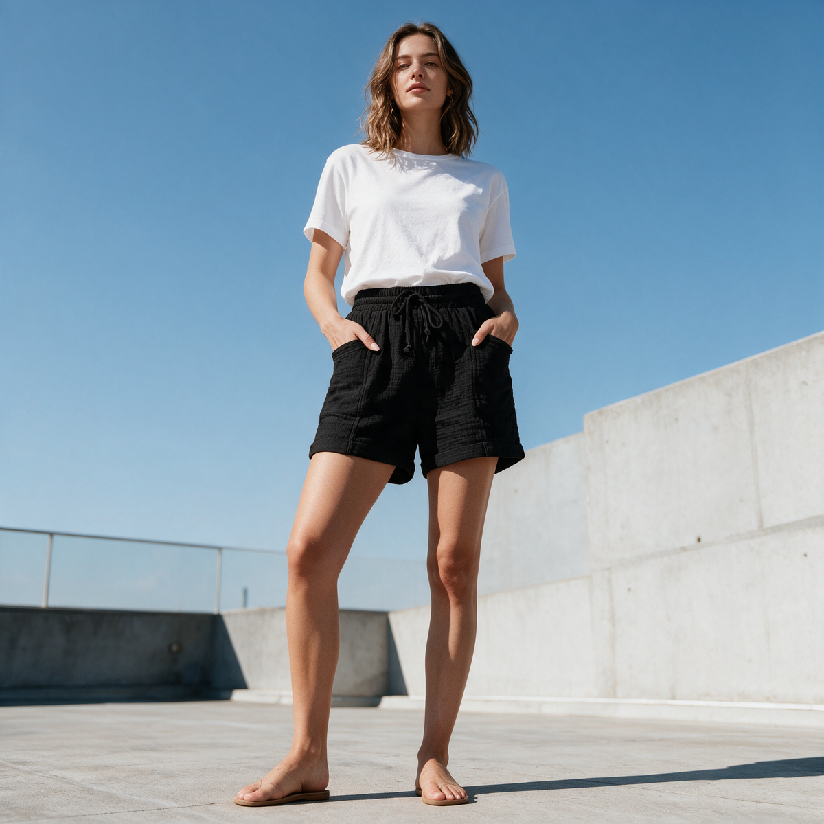 Model wearing the black Alexa gauze shorts on a concrete rooftop