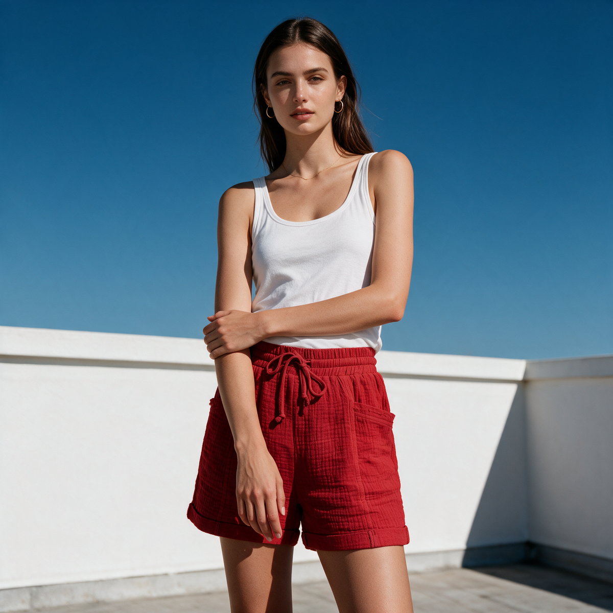 Model wearing the red Alexa gauze shorts on a rooftop against blue sky
