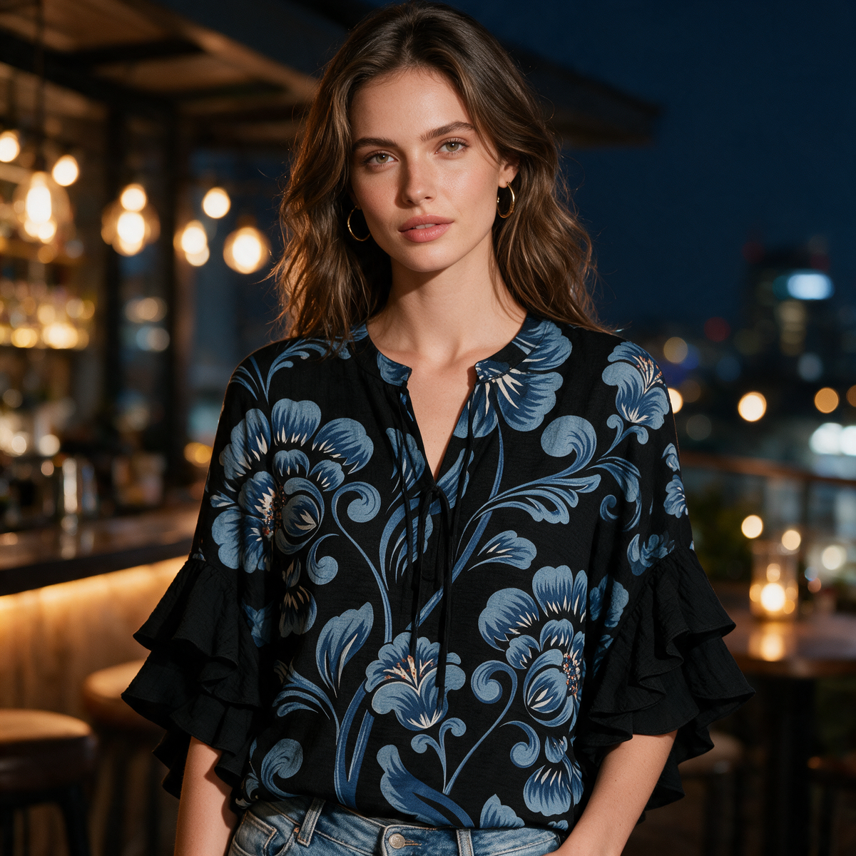 Model wearing the black Janessa blouse at an evening rooftop bar