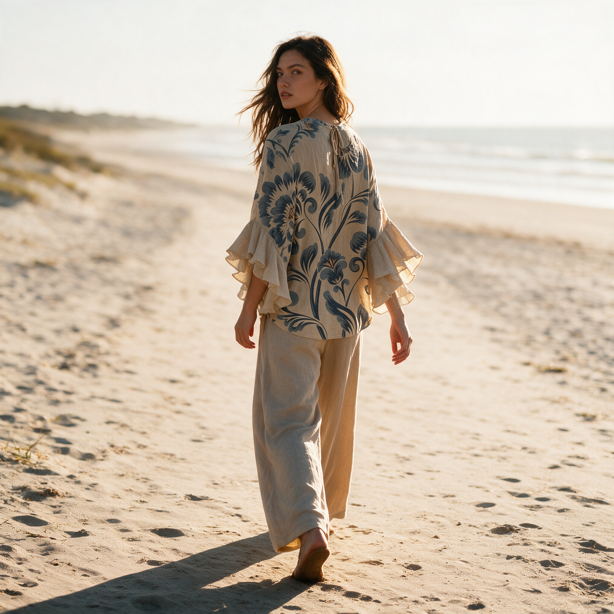 Model wearing the beige Janessa blouse on a coastal path at golden hour