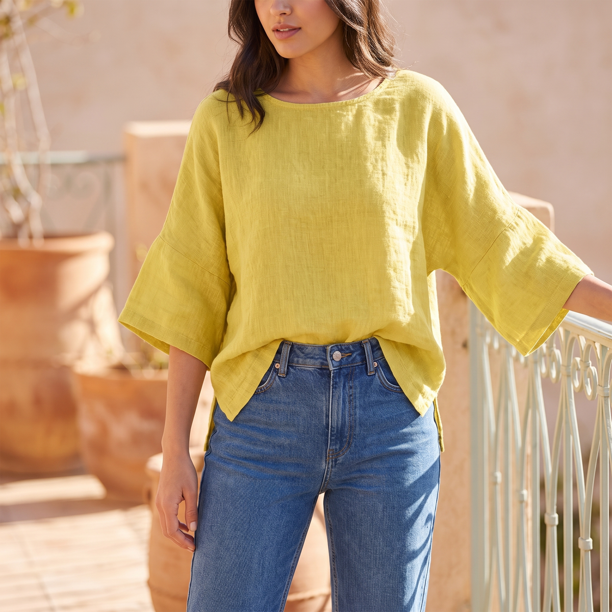 Woman on a sunlit balcony wearing the Yellow linen blouse
