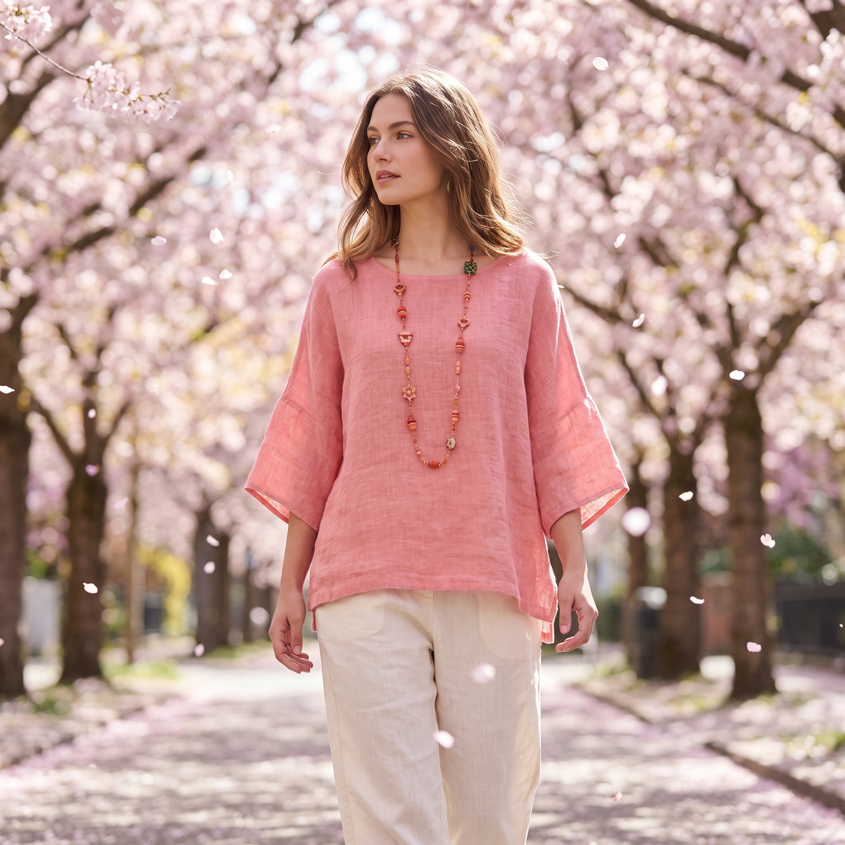 Woman in a blossom-lined street wearing the Pink linen blouse