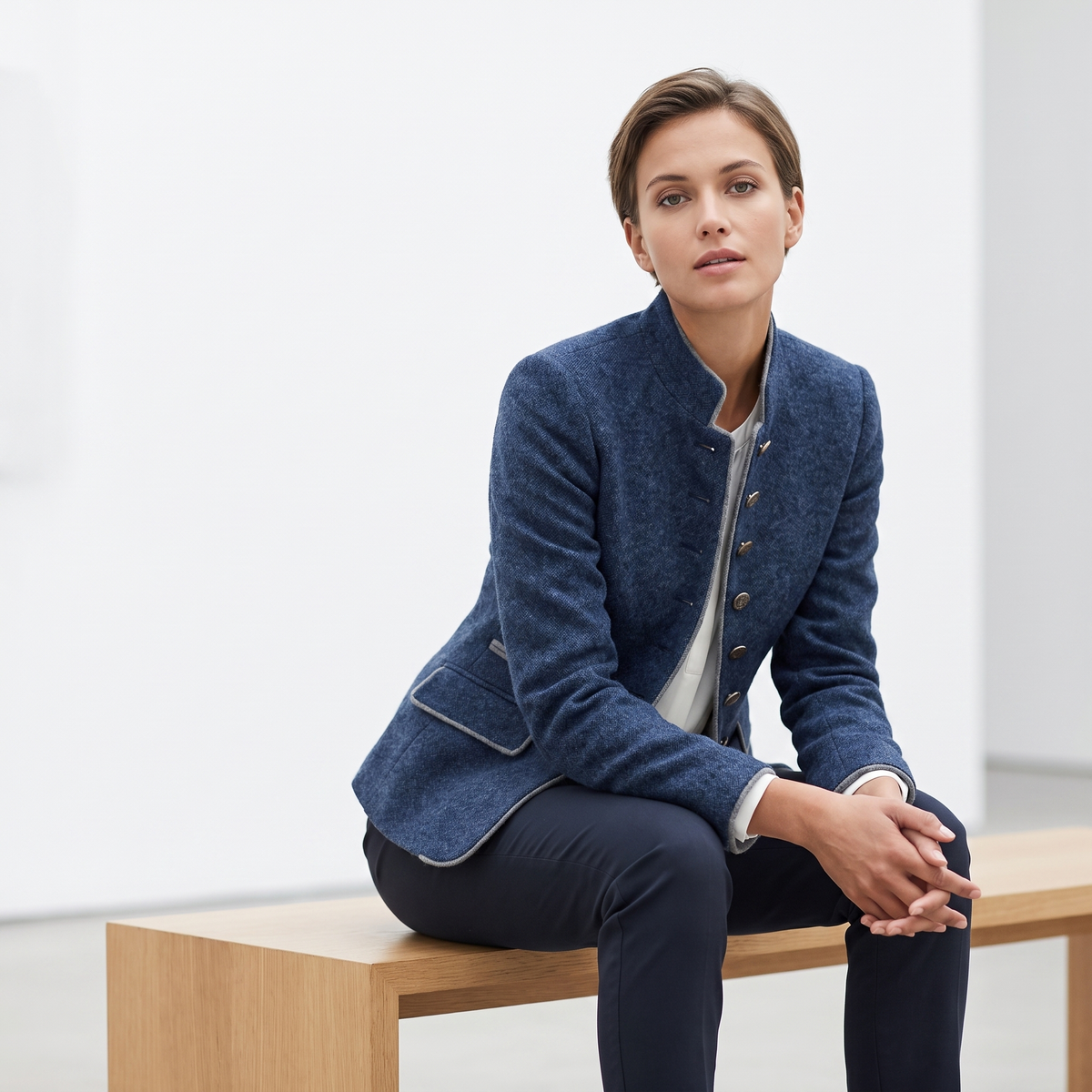 Woman on a gallery bench in the Blue contrast-trim blazer
