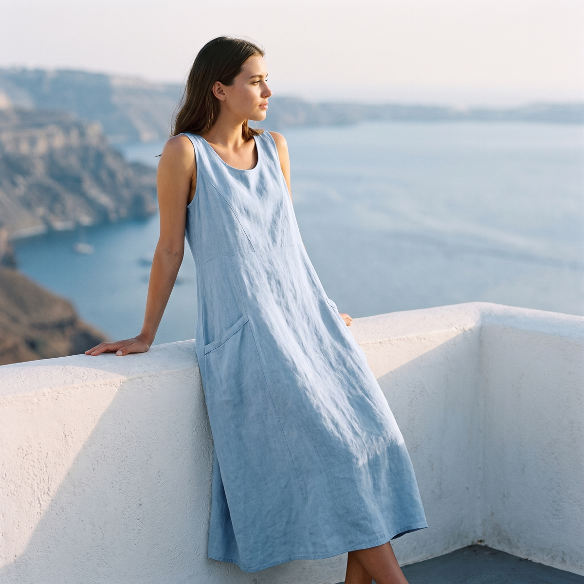 Woman on a balcony above the sea in the Light Blue linen midi dress