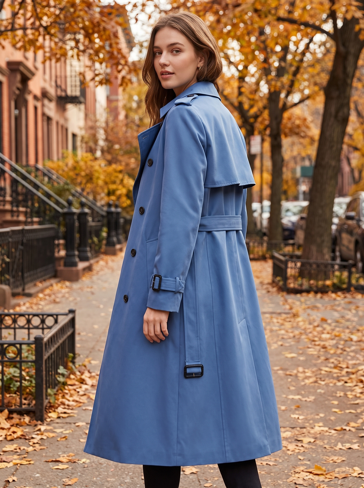 Aveline blue double breasted trench coat worn by a model on an autumn park path in autumn