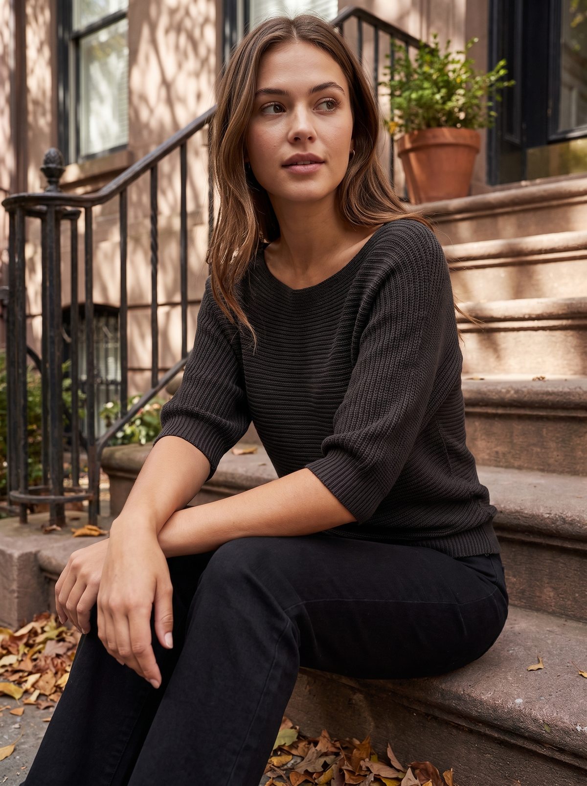 Giselle black three quarter sleeve knit sweater worn by a model on city townhouse steps in autumn