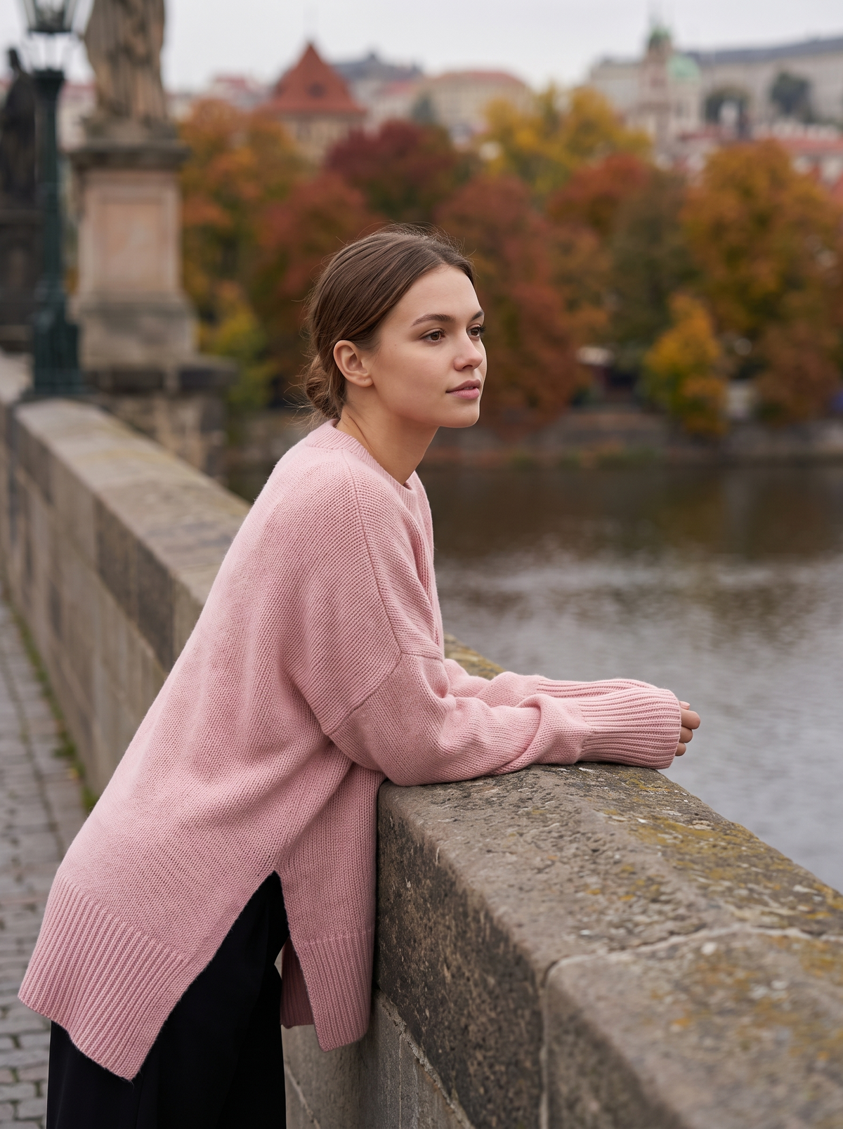 Aurelia pink merino wool asymmetric sweater worn by a model on a city bridge in autumn