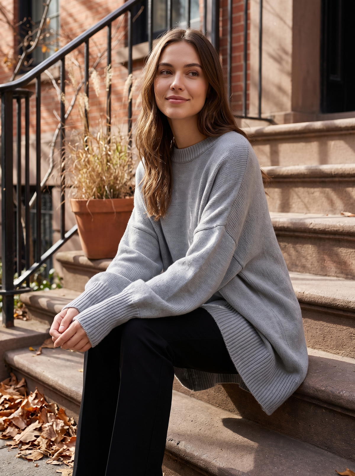 Aurelia grey merino wool asymmetric sweater worn by a model on city townhouse steps in autumn