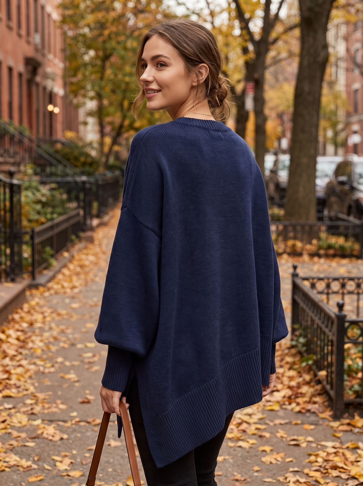Aurelia navy blue merino wool asymmetric sweater worn by a model on an autumn park path in autumn