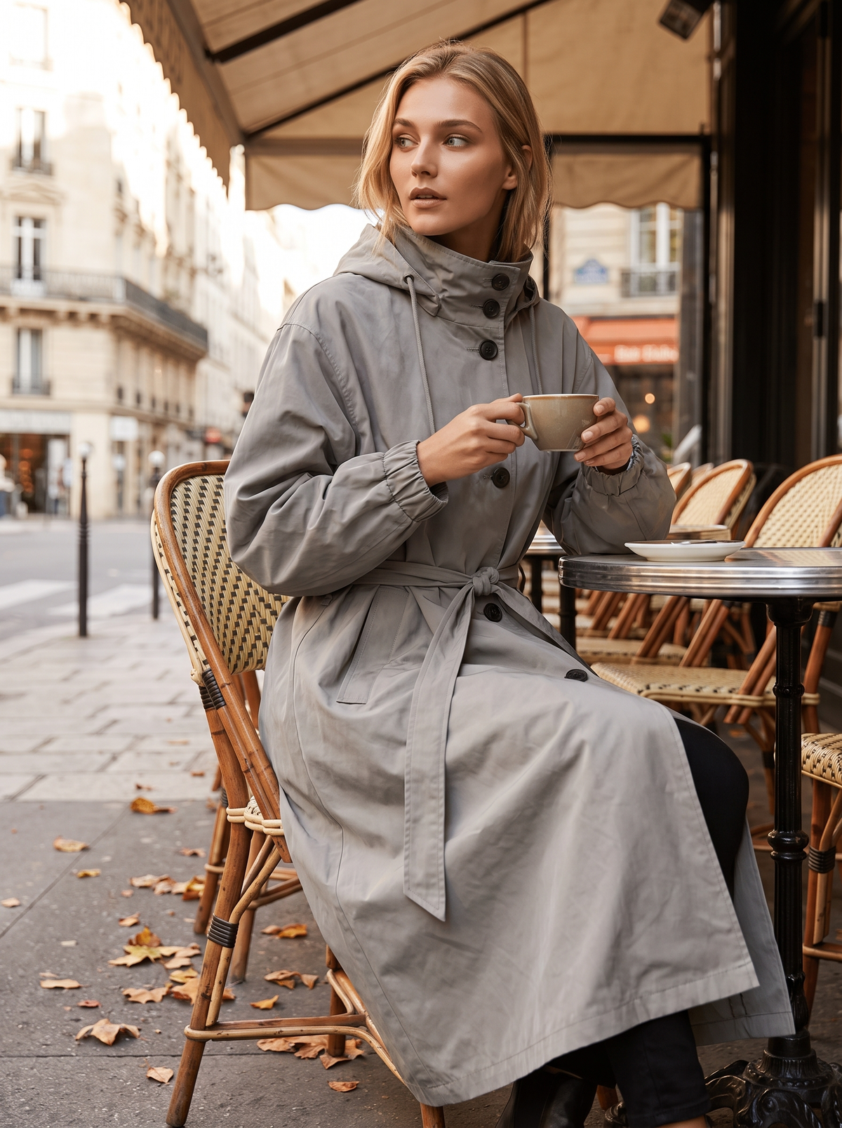 Mirabelle grey oversized trench coat worn by a model at an outdoor city cafe in autumn