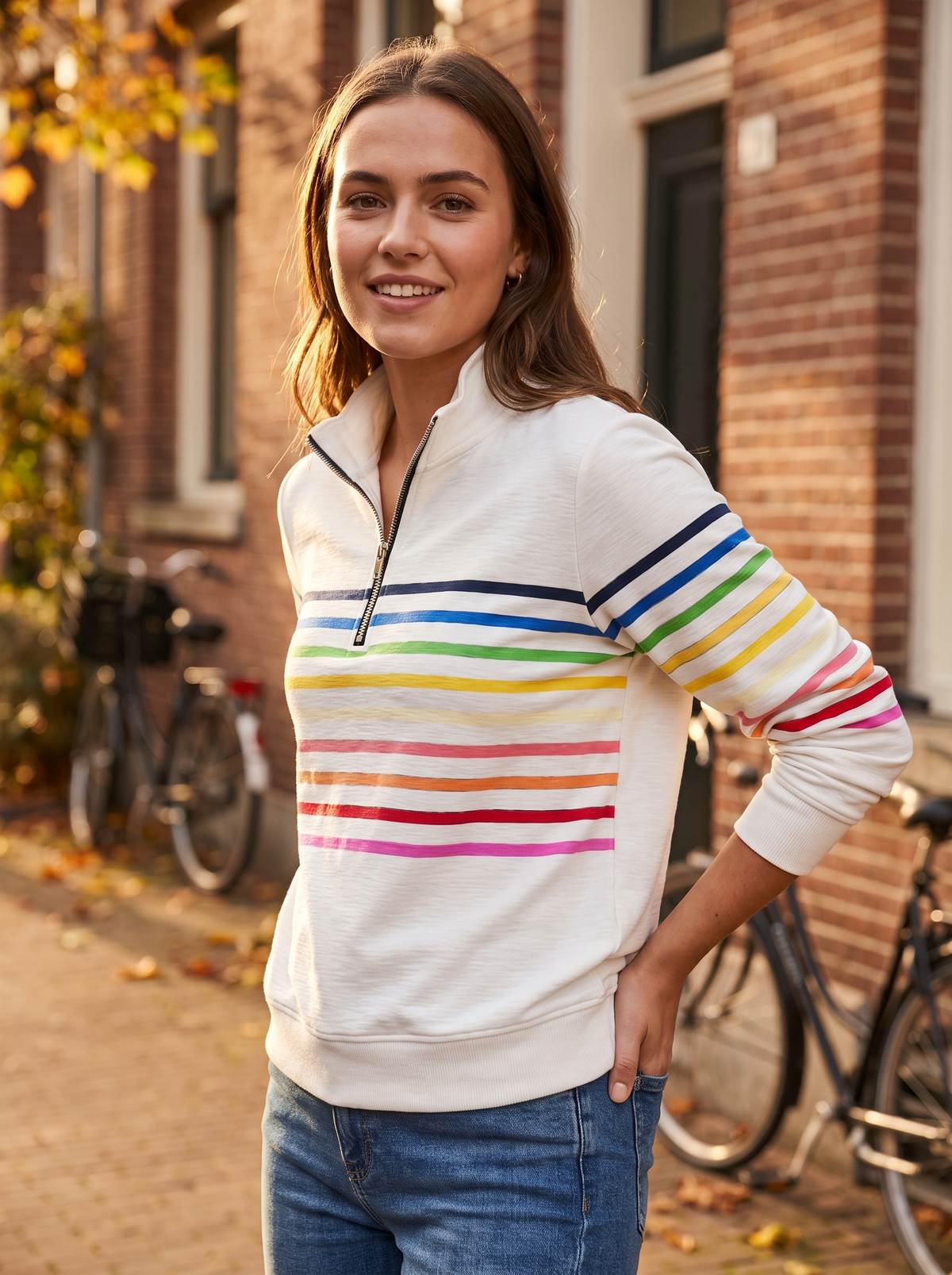 Zephyrine white striped half zip sweatshirt worn by a model against a brick city facade in autumn