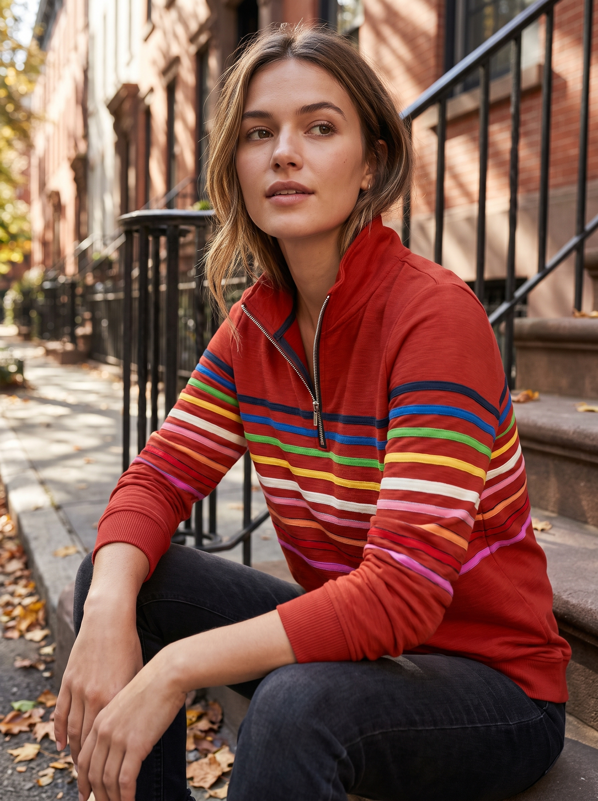 Zephyrine red striped half zip sweatshirt worn by a model on city townhouse steps in autumn