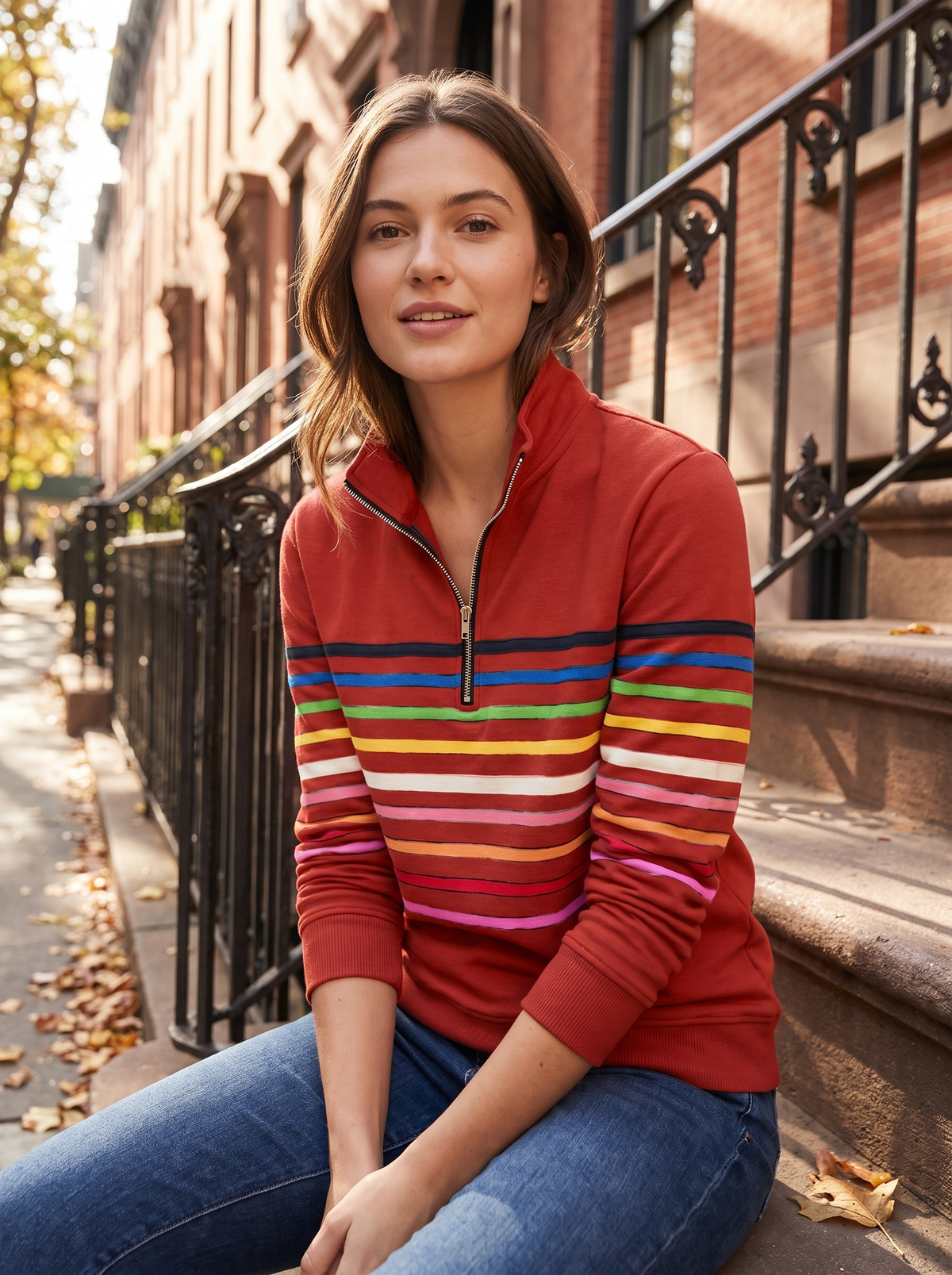 Thomasine red half zip sweatshirt worn by a model on city townhouse steps in autumn