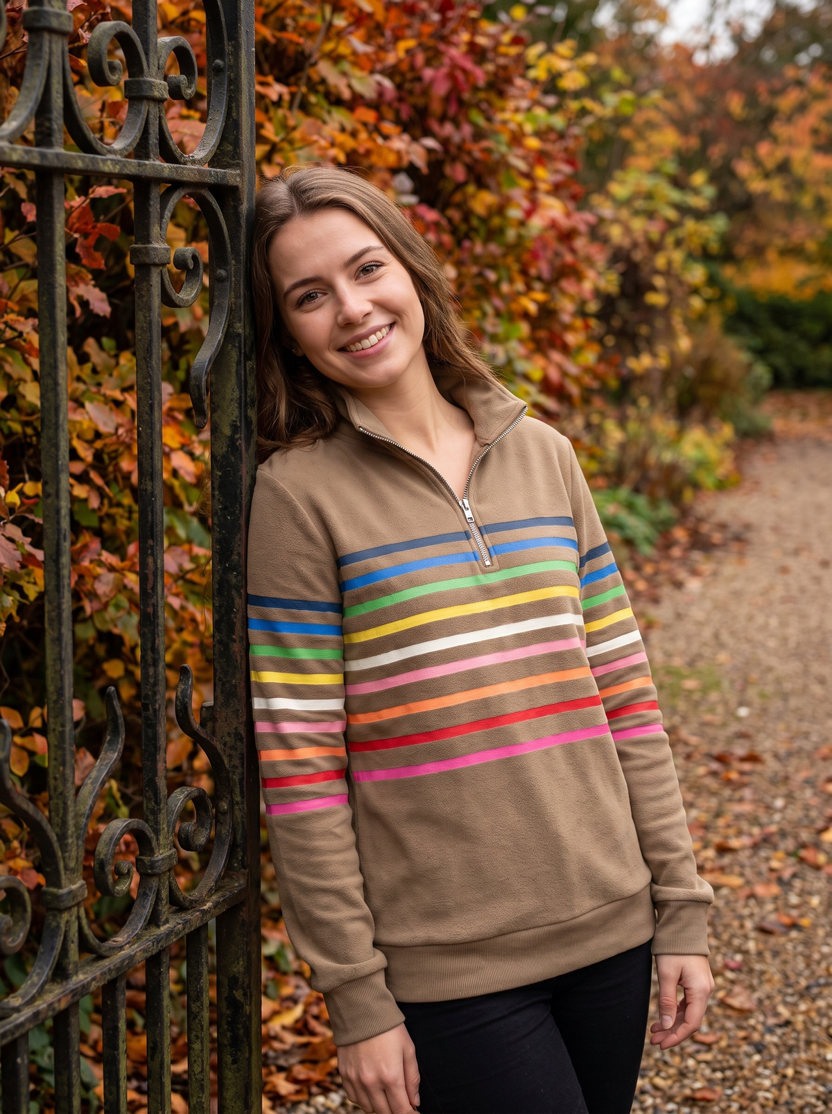 Thomasine khaki half zip sweatshirt worn by a model at a park gate in autumn