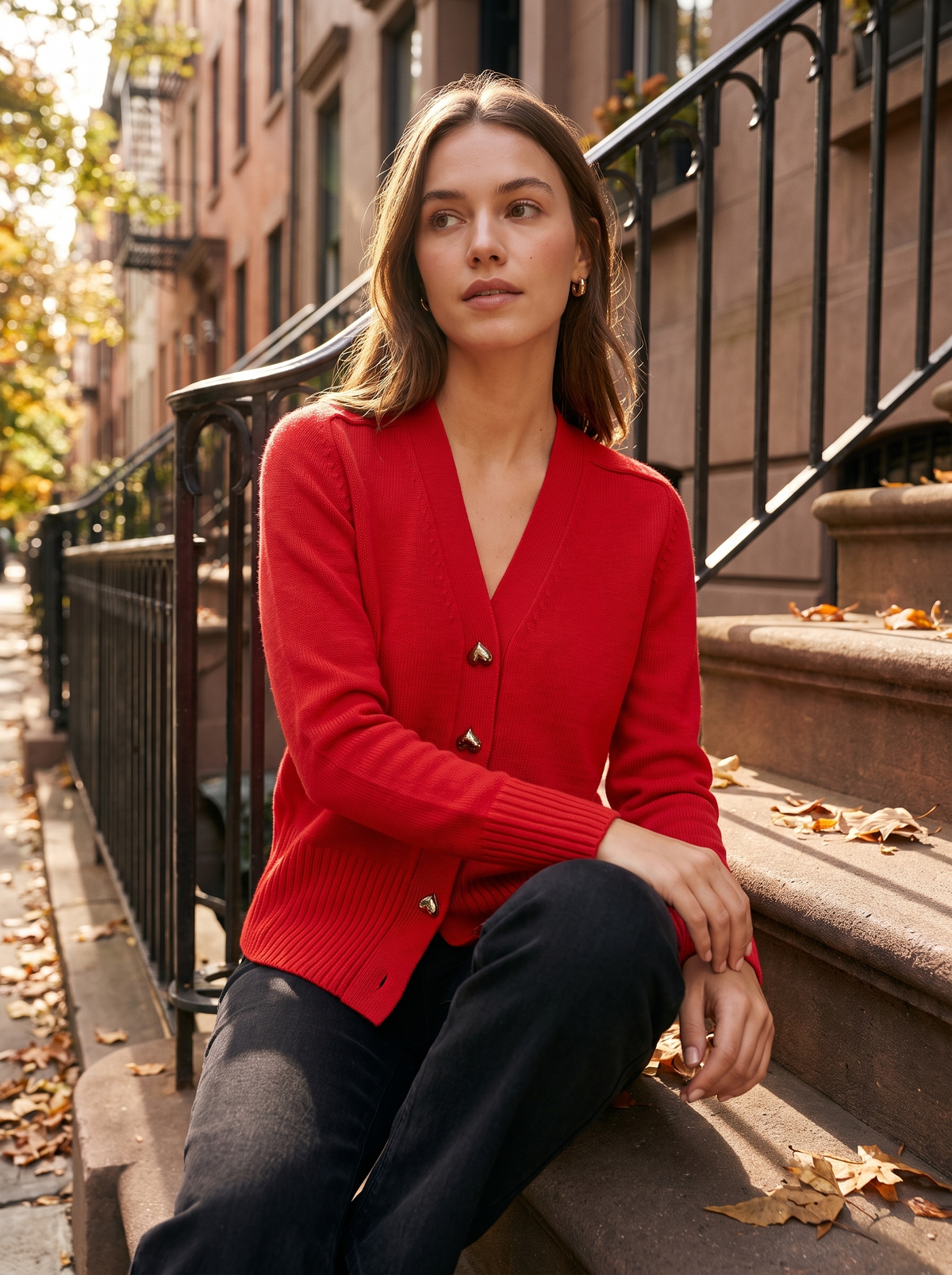 Yolande red ribbed knit cardigan worn by a model on city townhouse steps in autumn