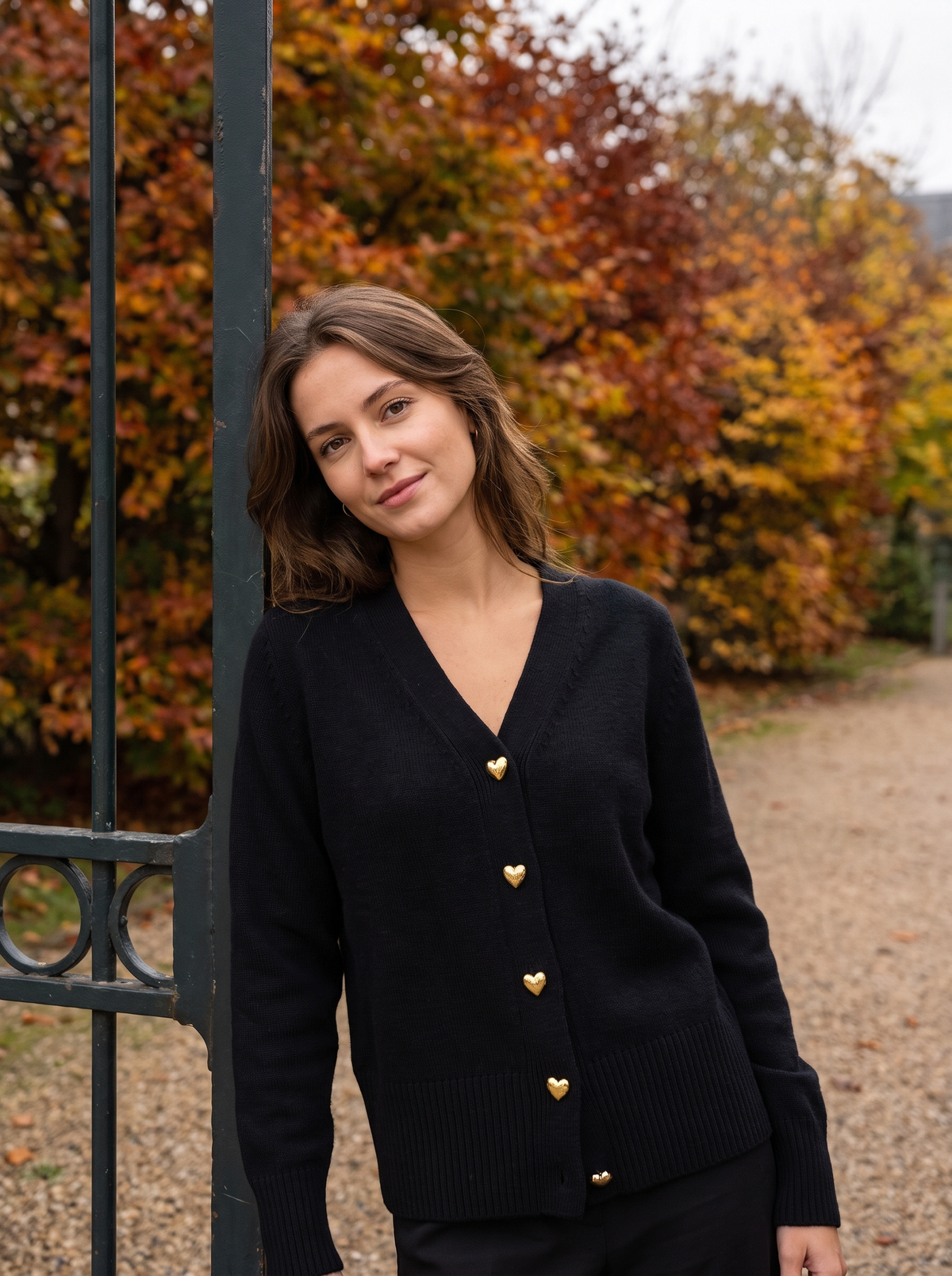 Yolande black ribbed knit cardigan worn by a model at a park gate in autumn