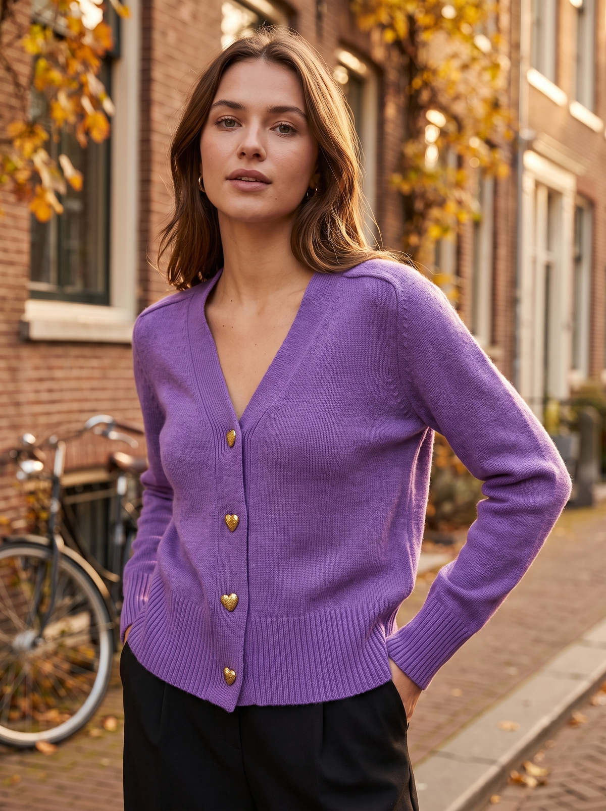 Yolande purple ribbed knit cardigan worn by a model against a brick city facade in autumn