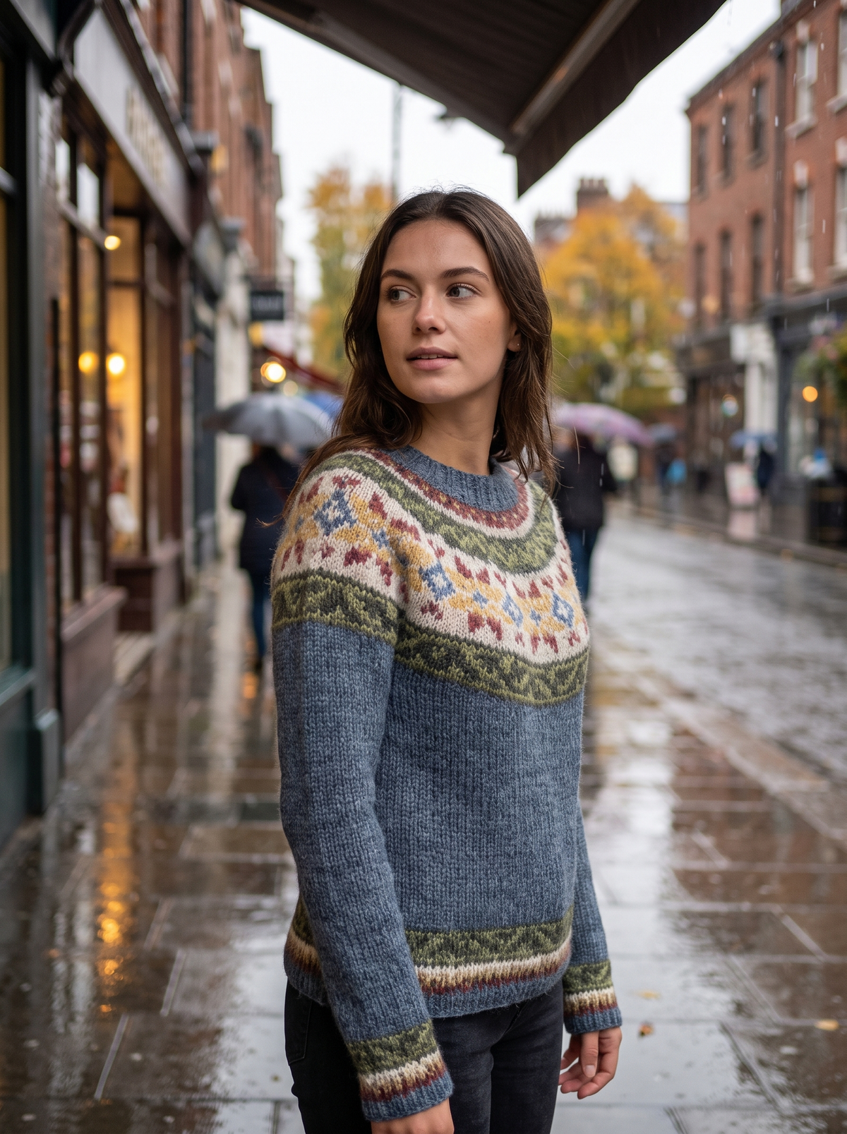 Vespera grey floral crew neck knit sweater worn by a model under a shop awning in the rain in autumn