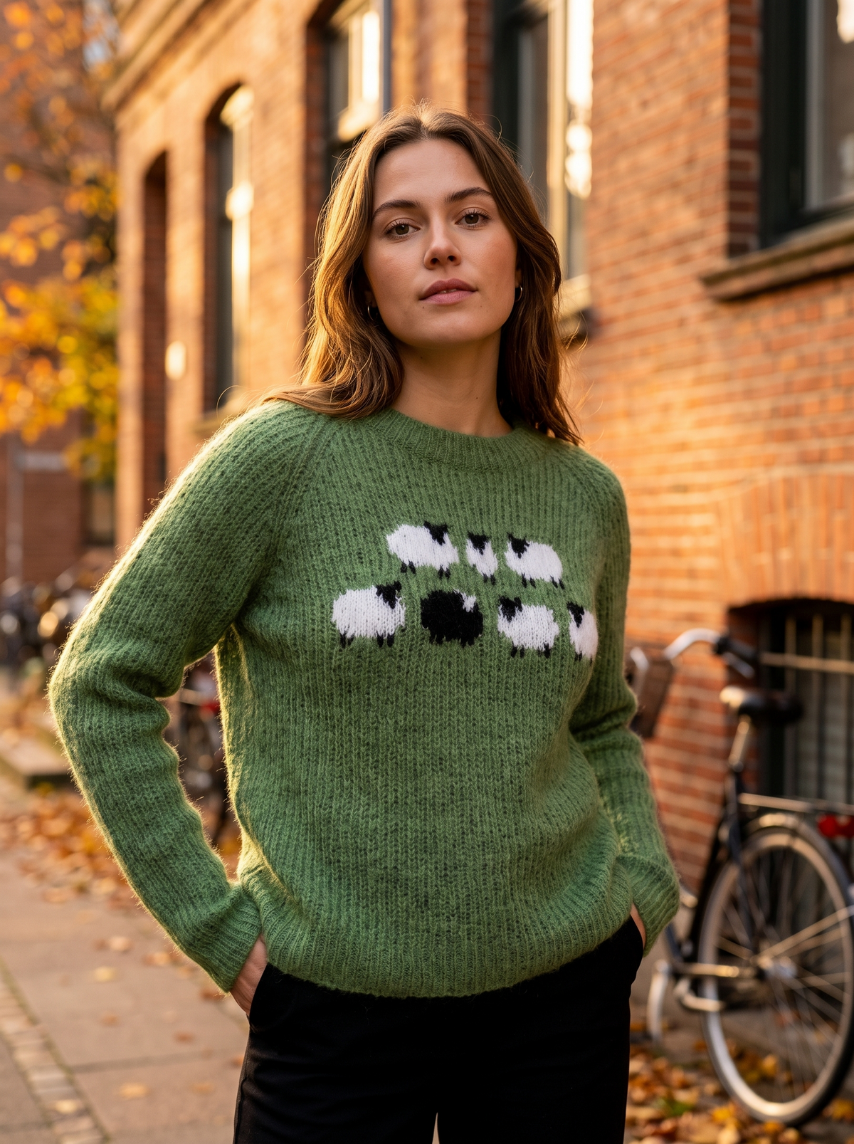 Vespera green crew neck knit sweater worn by a model against a brick city facade in autumn