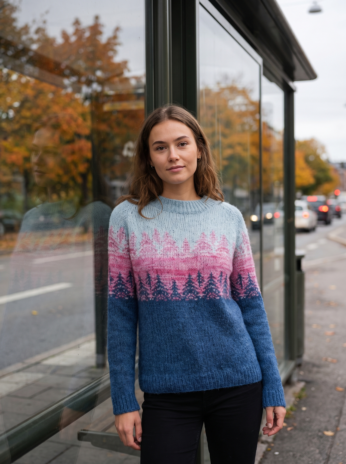 Vespera blue pink crew neck knit sweater worn by a model by a city bus shelter in autumn