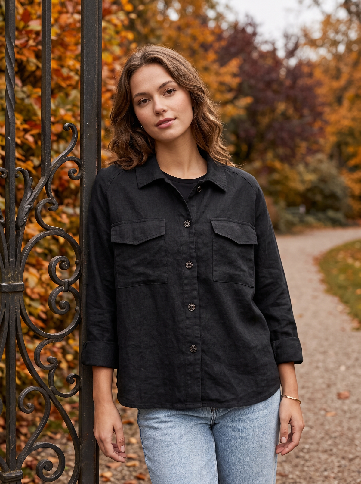 Linnea black cotton shirt jacket worn by a model at a park gate in autumn