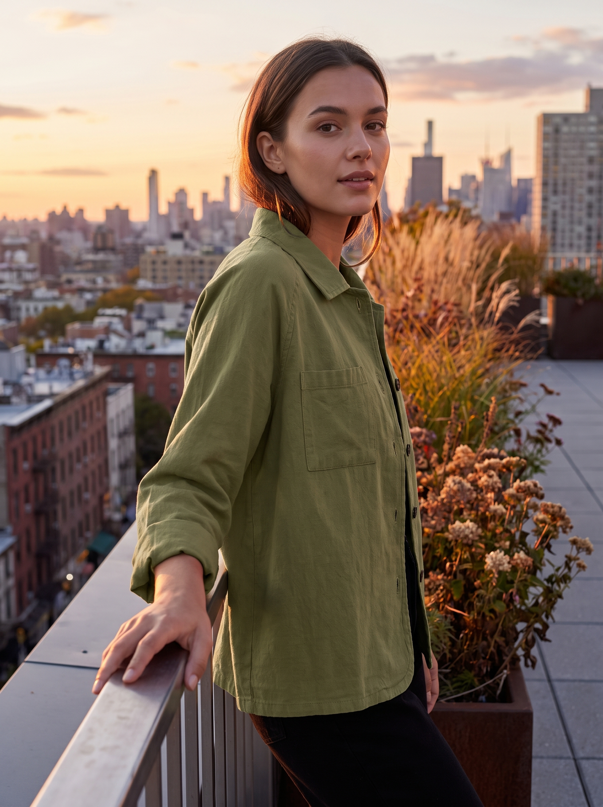 Linnea olive green cotton shirt jacket worn by a model on a city rooftop terrace in autumn