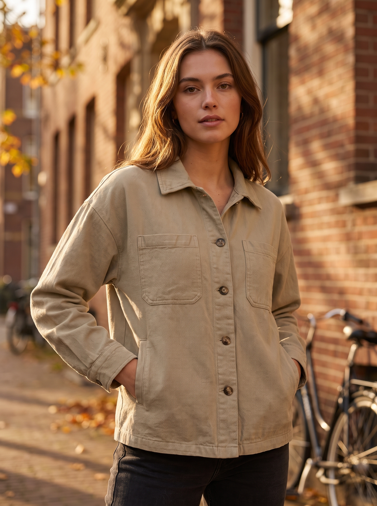 Linnea khaki cotton shirt jacket worn by a model against a brick city facade in autumn
