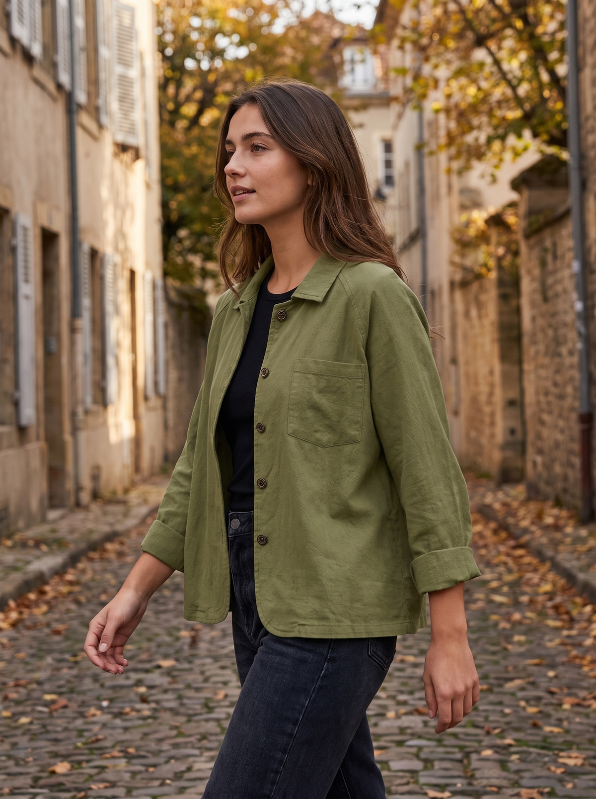 Linnea olive green cotton shirt jacket worn by a model in a cobbled city lane in autumn