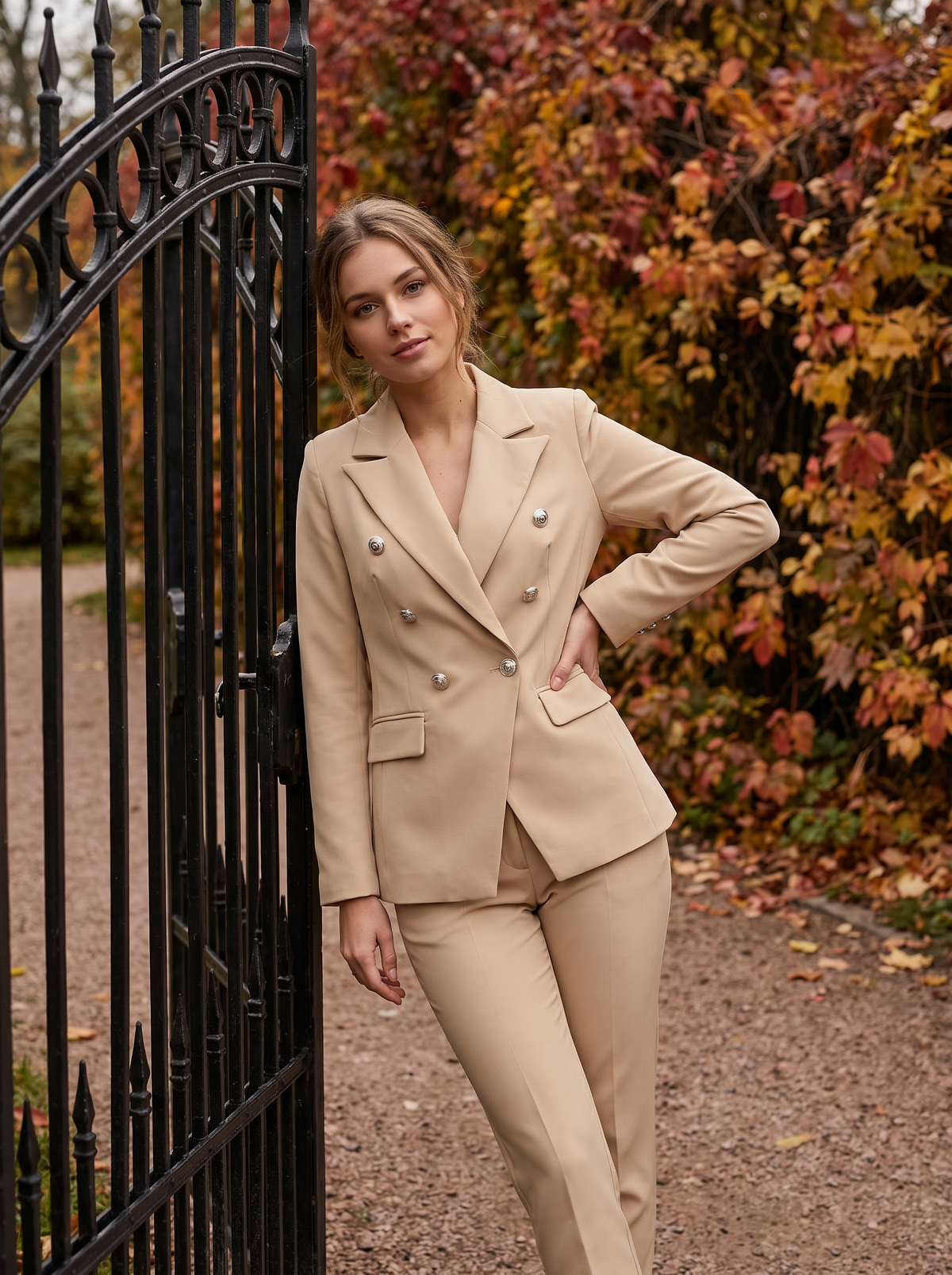 Xaviera beige double breasted blazer suit set worn by a model at a park gate in autumn