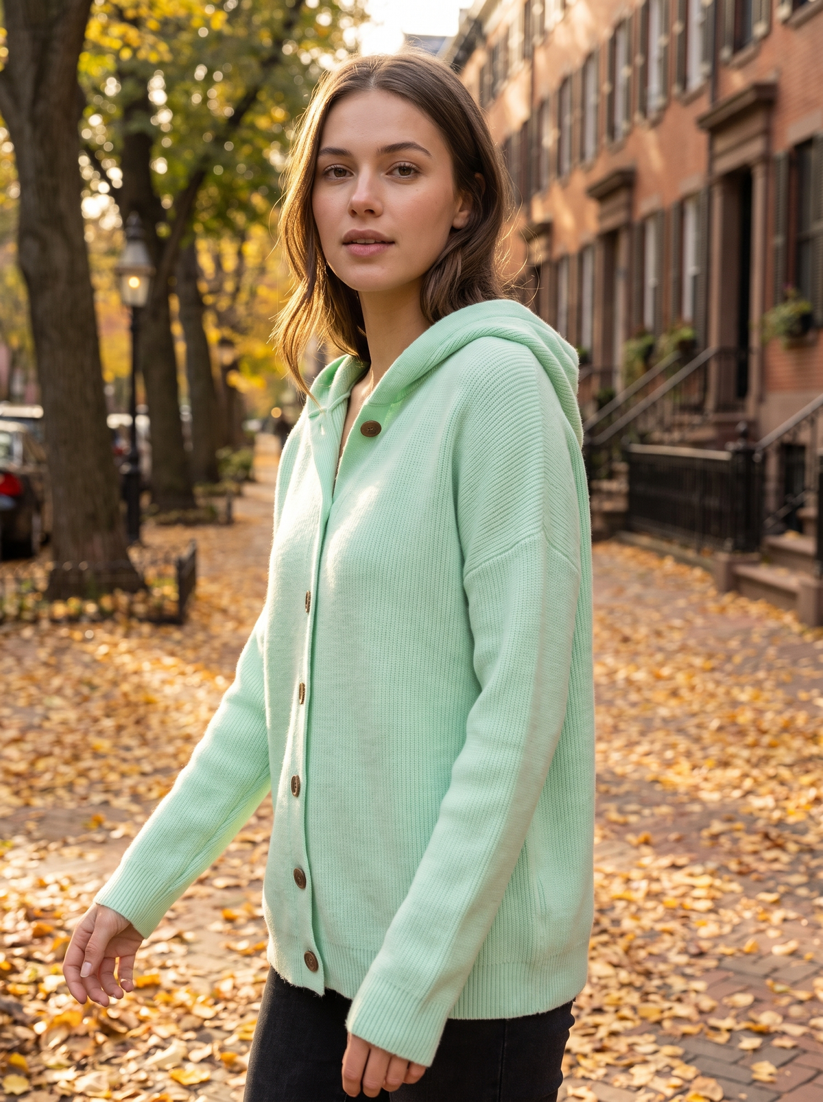 Bellamy green hooded cardigan worn by a model walking a leafy city street in autumn