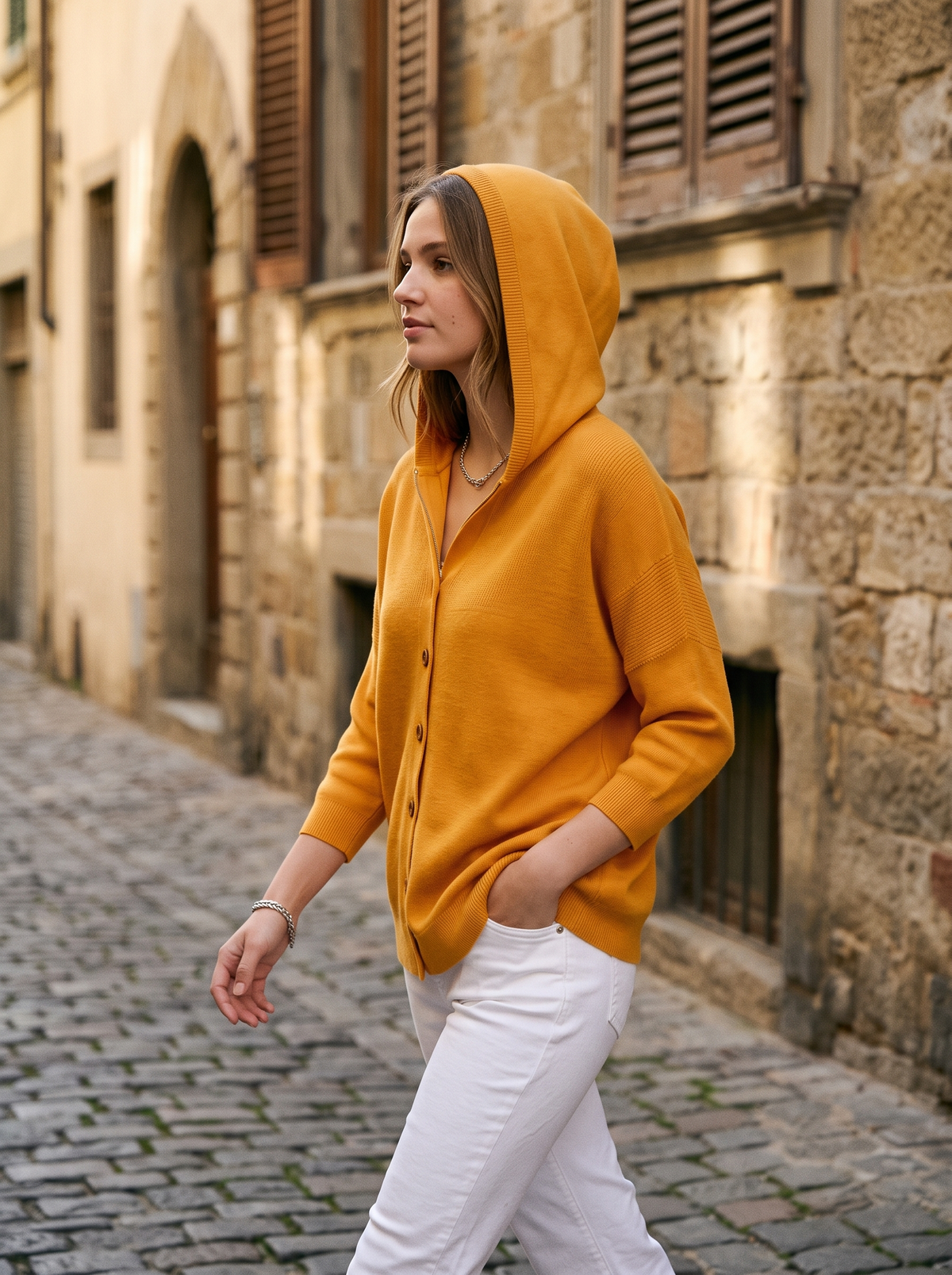 Bellamy orange hooded cardigan worn by a model in a cobbled city lane in autumn