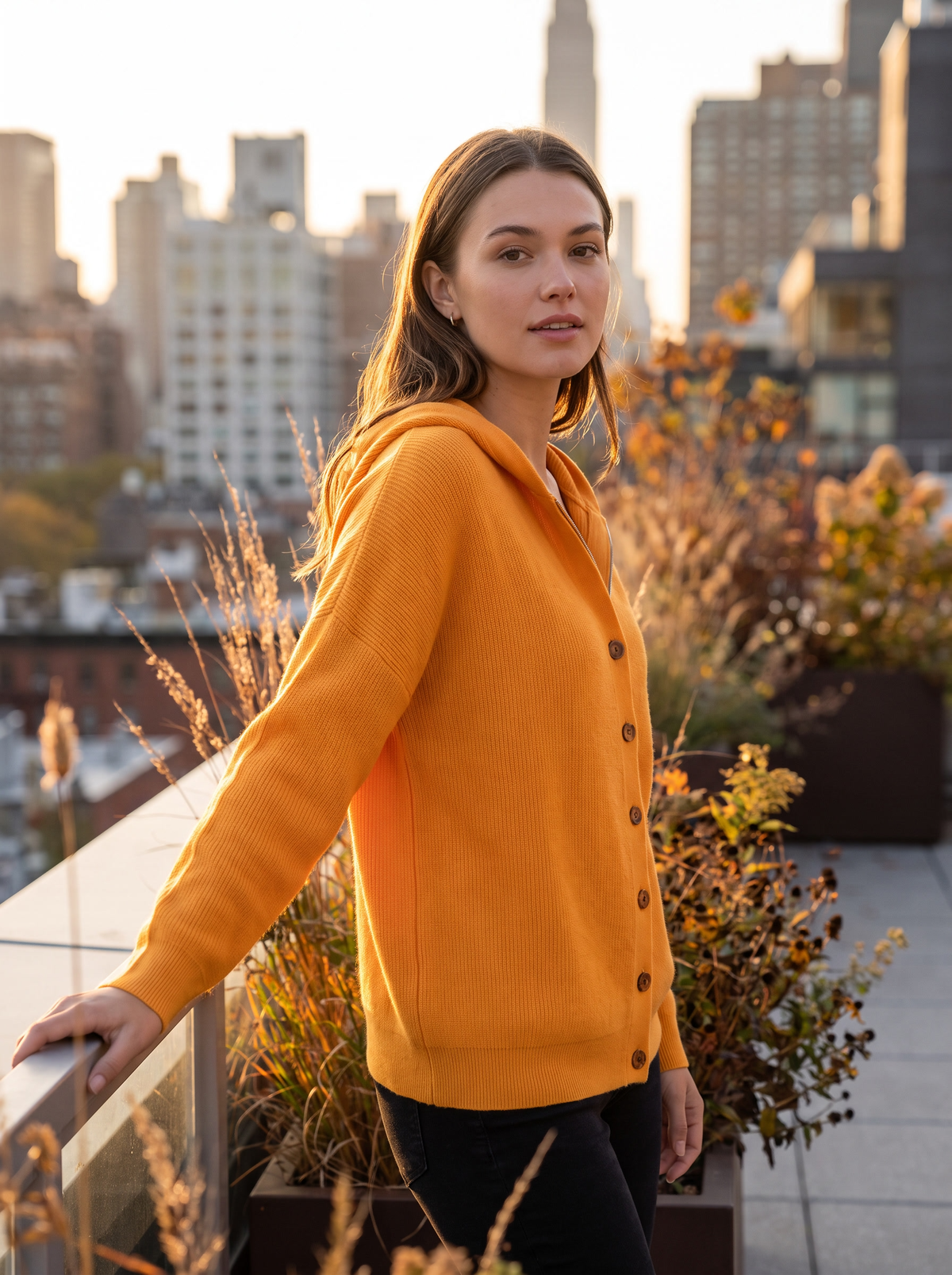 Bellamy orange hooded cardigan worn by a model on a city rooftop terrace in autumn