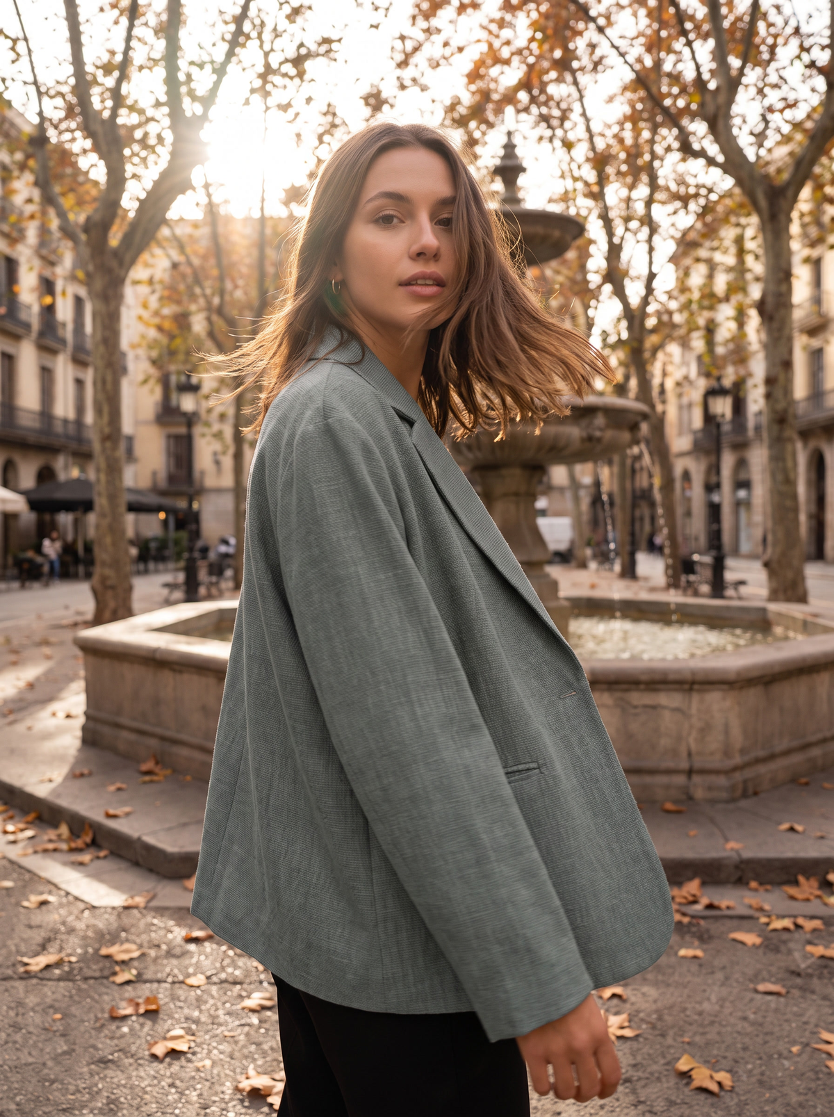 Eulalie grey oversized blazer worn by a model by a fountain in a city square in autumn