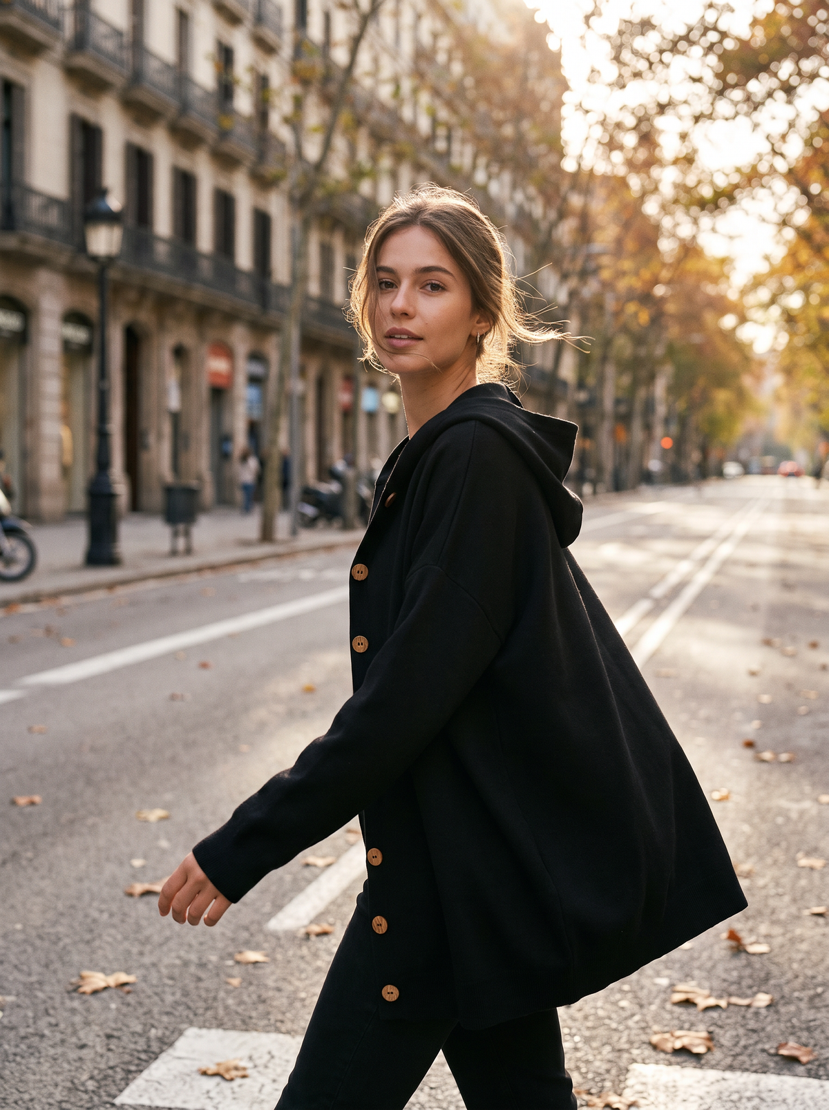 Bellamy black hooded cardigan worn by a model crossing a city boulevard in autumn