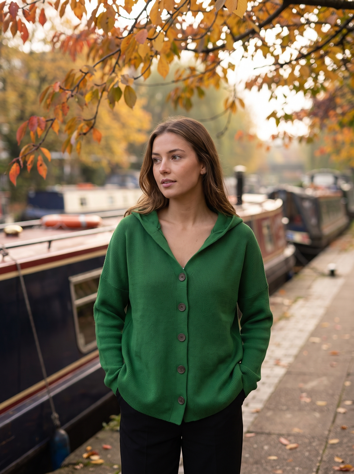Bellamy dark green hooded cardigan worn by a model on a city canal towpath in autumn