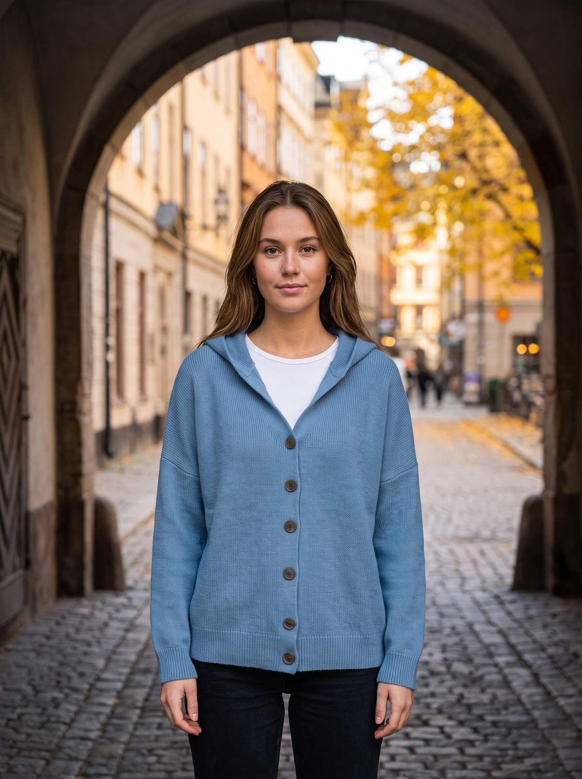 Bellamy blue hooded cardigan worn by a model in a stone archway in autumn