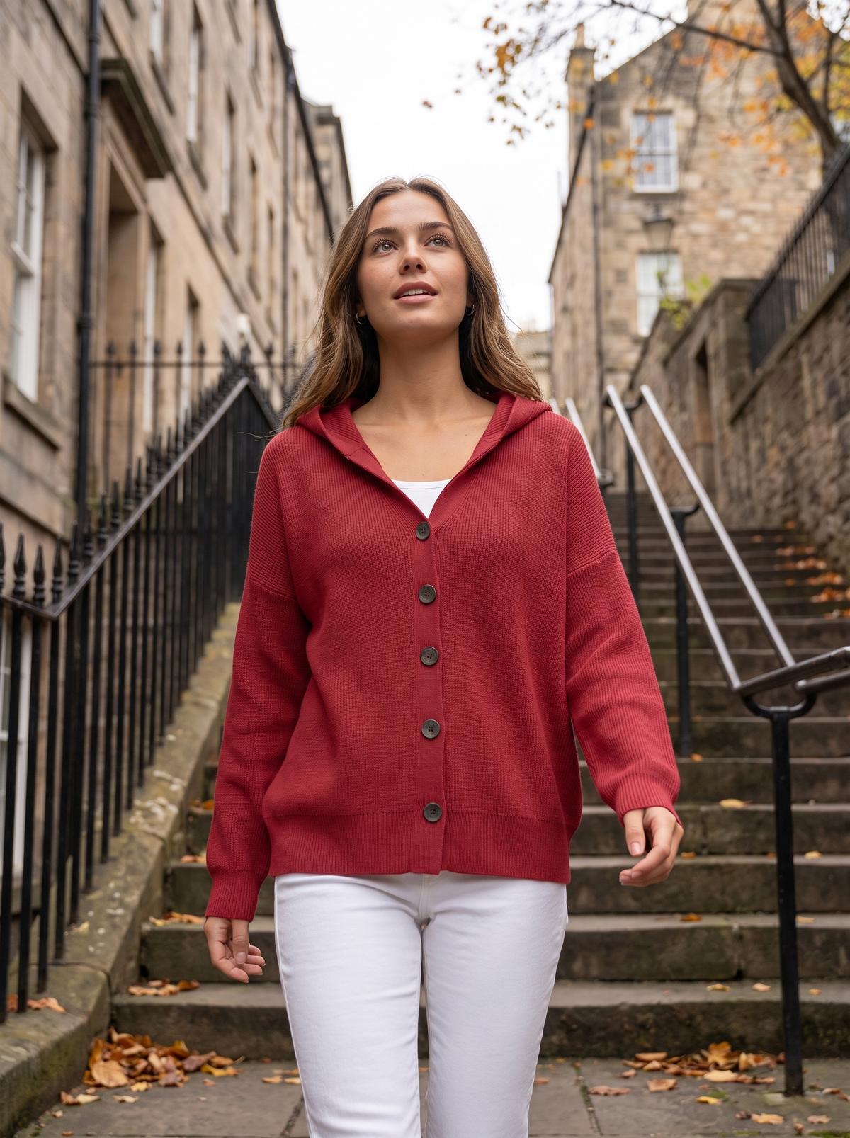 Bellamy red hooded cardigan worn by a model on iron railed city steps in autumn