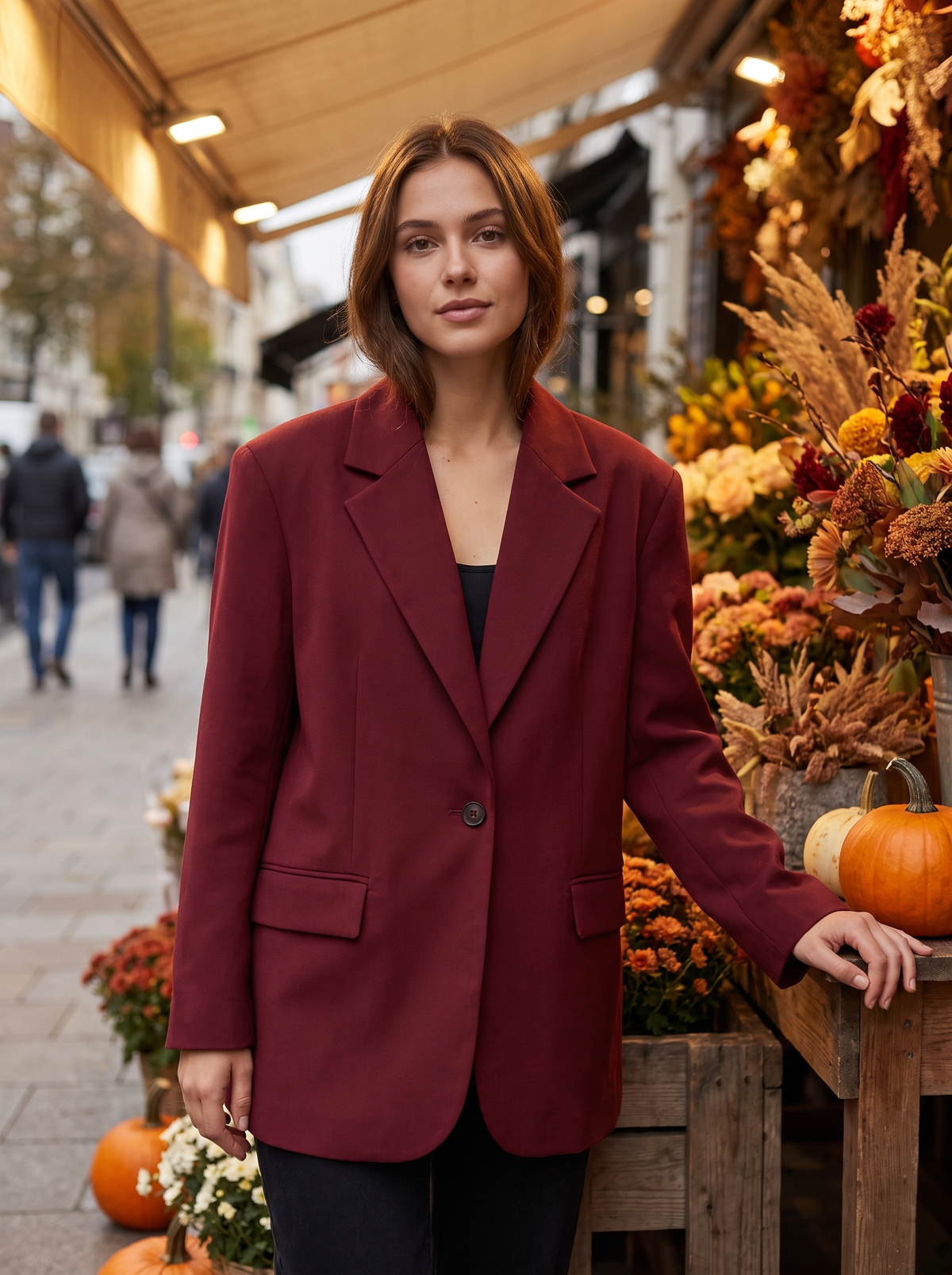 Eulalie burgundy oversized blazer worn by a model beside a city flower stall in autumn