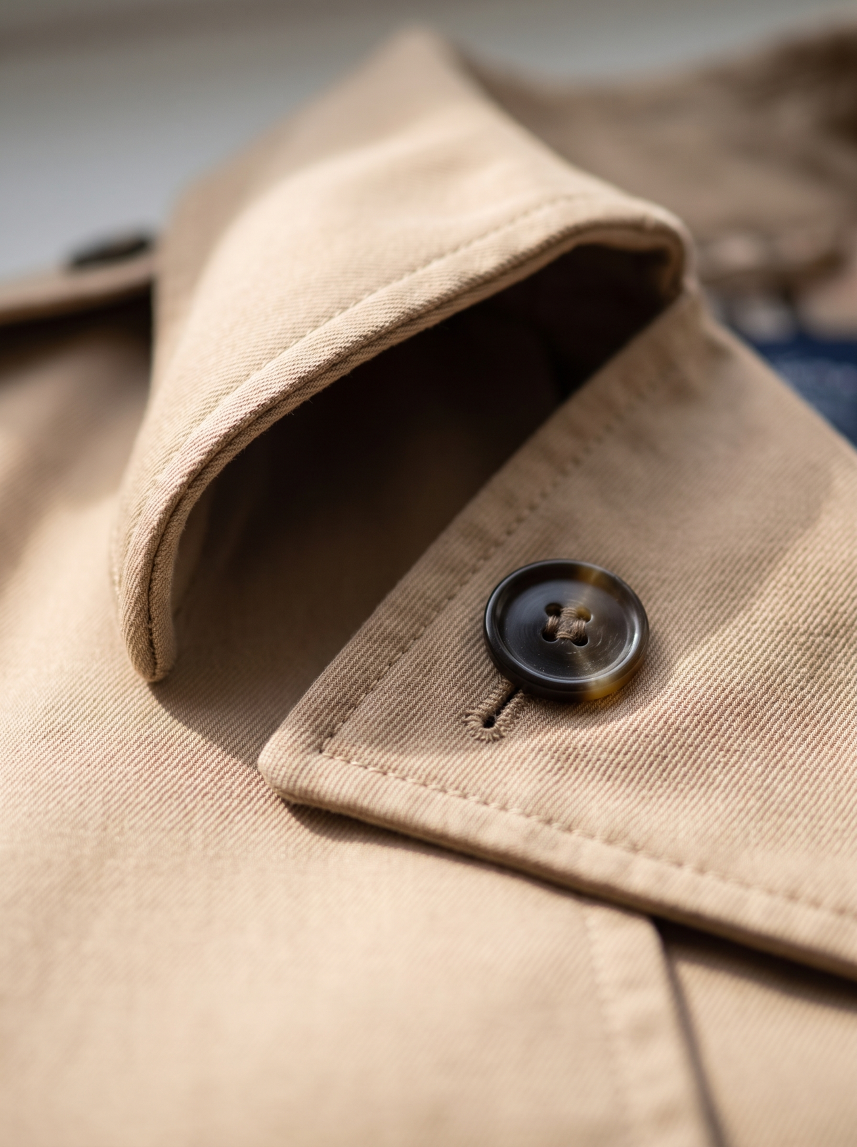 Detail of the Aveline double breasted trench coat showing its material and finish